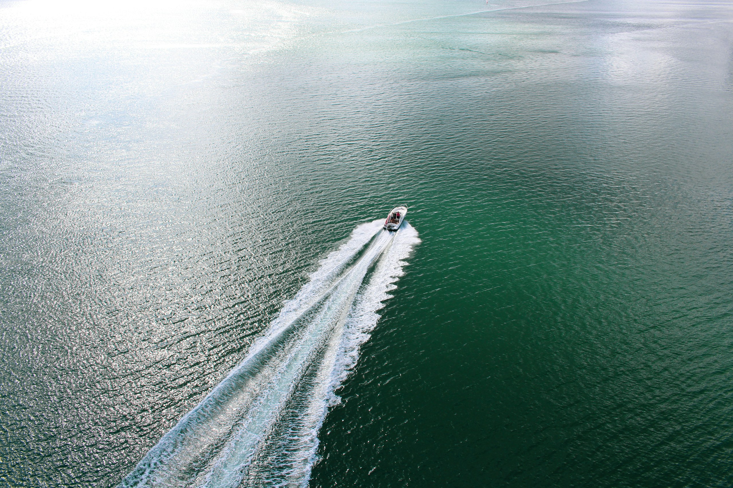 A motorboat running fast across open water, leaving a long white wake