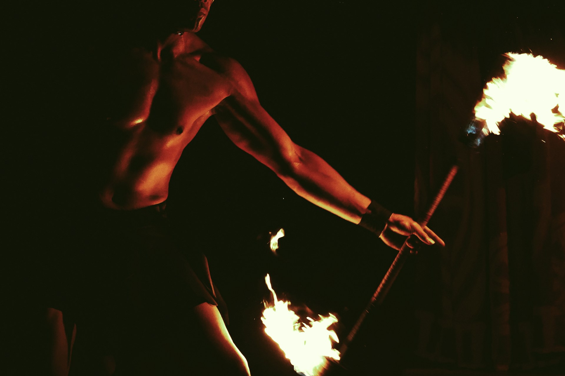 A performer spinning lit fire torches after dark